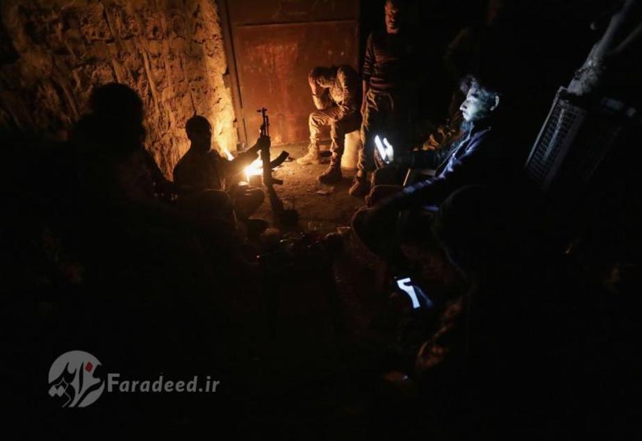 جنگجویان گروه موسوم به ارتش آزاد سوریه در حال گرم کردن خود به دور آتش در شهر تادف در استان حلب، سوریه