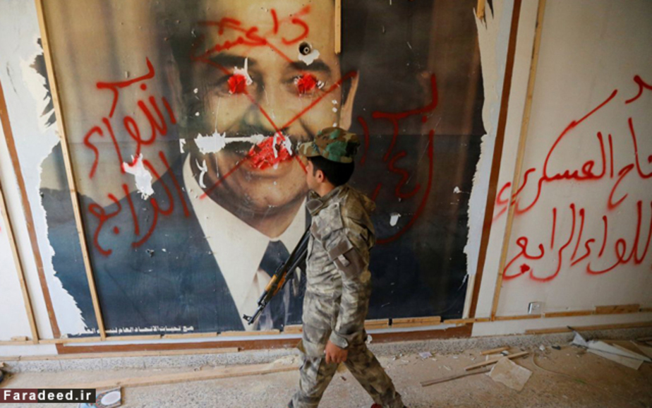 عبور یکی از مبارزان شیعی از مقابل تصویر صدام حسین در فلوجه، عراق