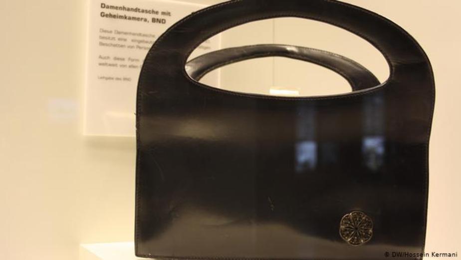 وسط گل حک شده در کناره این کیف‌ دستی، عدسی یک دوربین‌مخفی کوچک قرار دارد